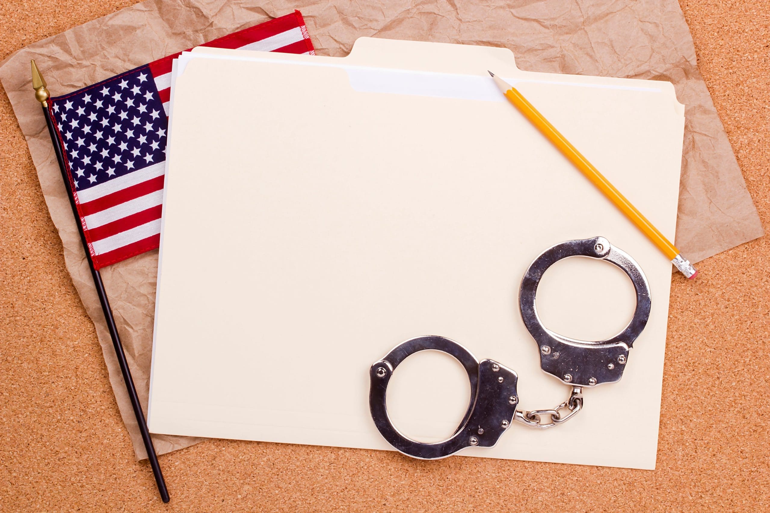 Handcuffs and an american flag on a corkboard.