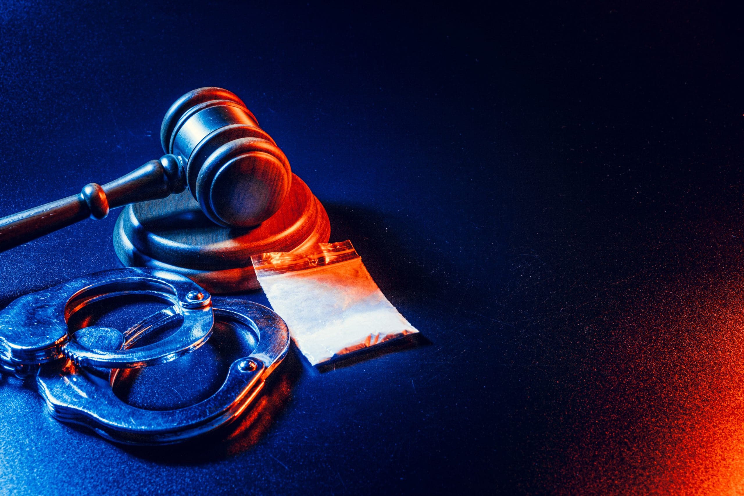 A gavel and handcuffs on a blue background.