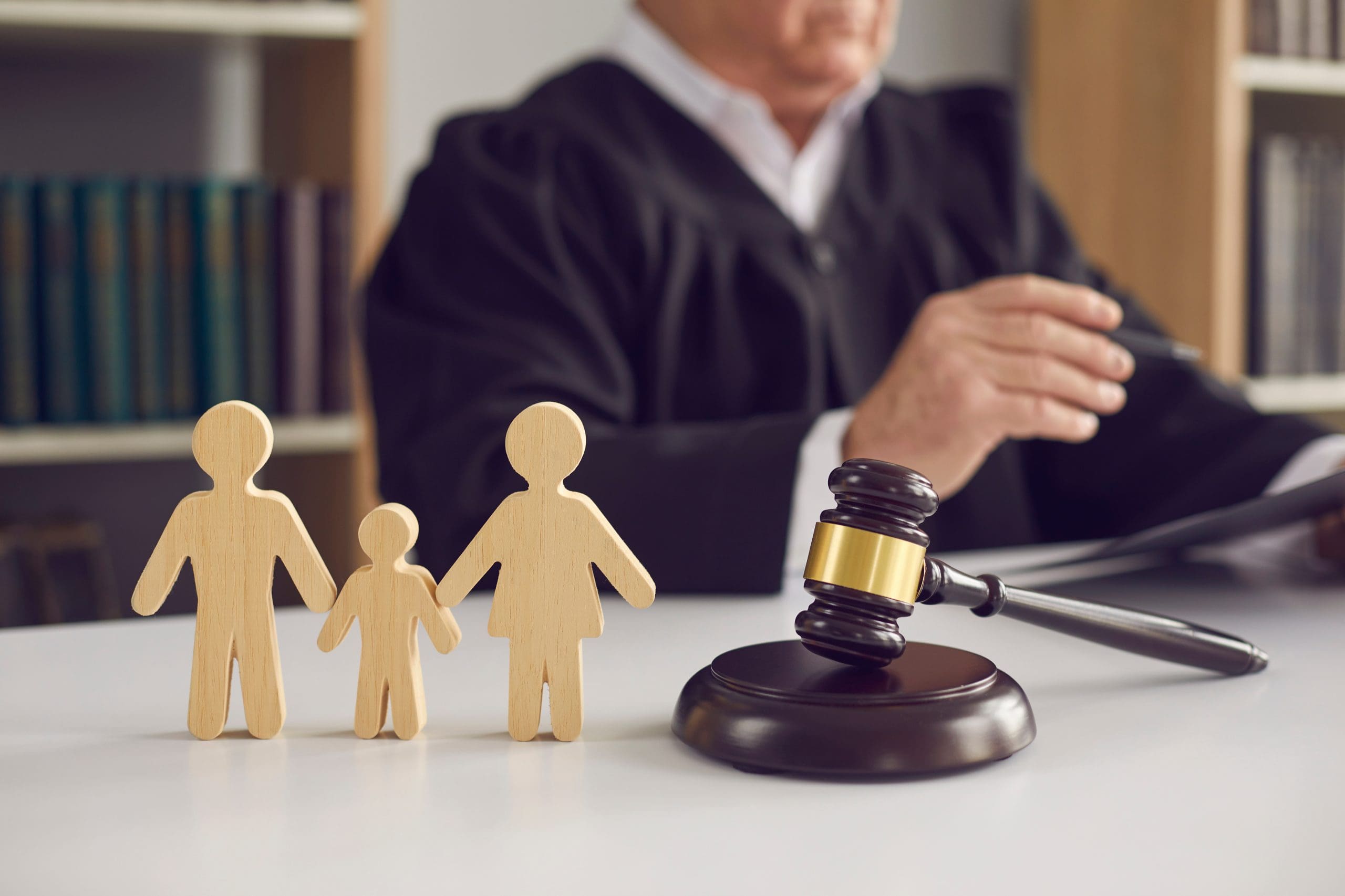 A wooden figure of a judge with a gavel and a family in front of it.