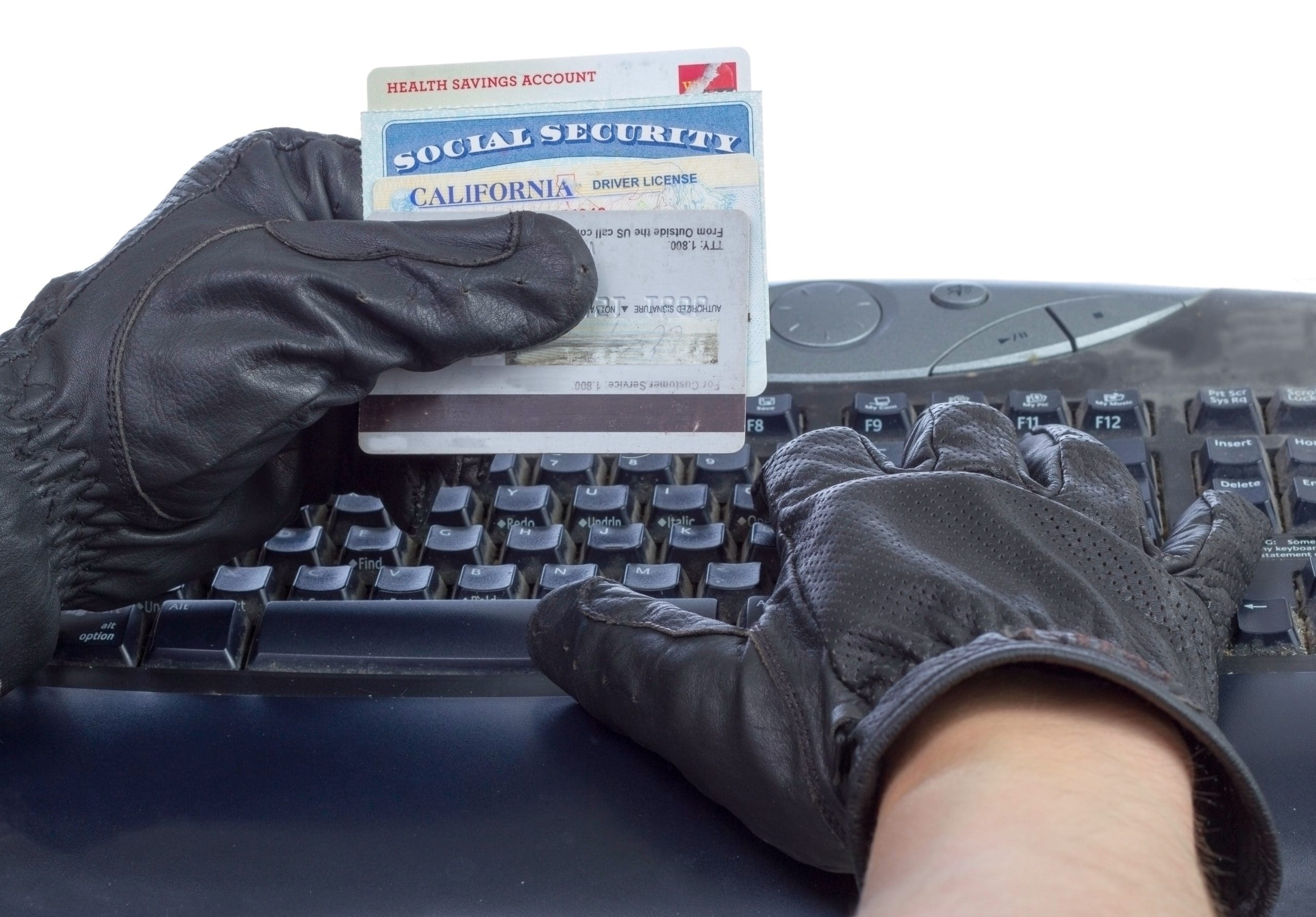 An individual with black gloves carefully handling an SSI card on a keyboard, potentially indicating involvement in identity theft or the need for expungement.