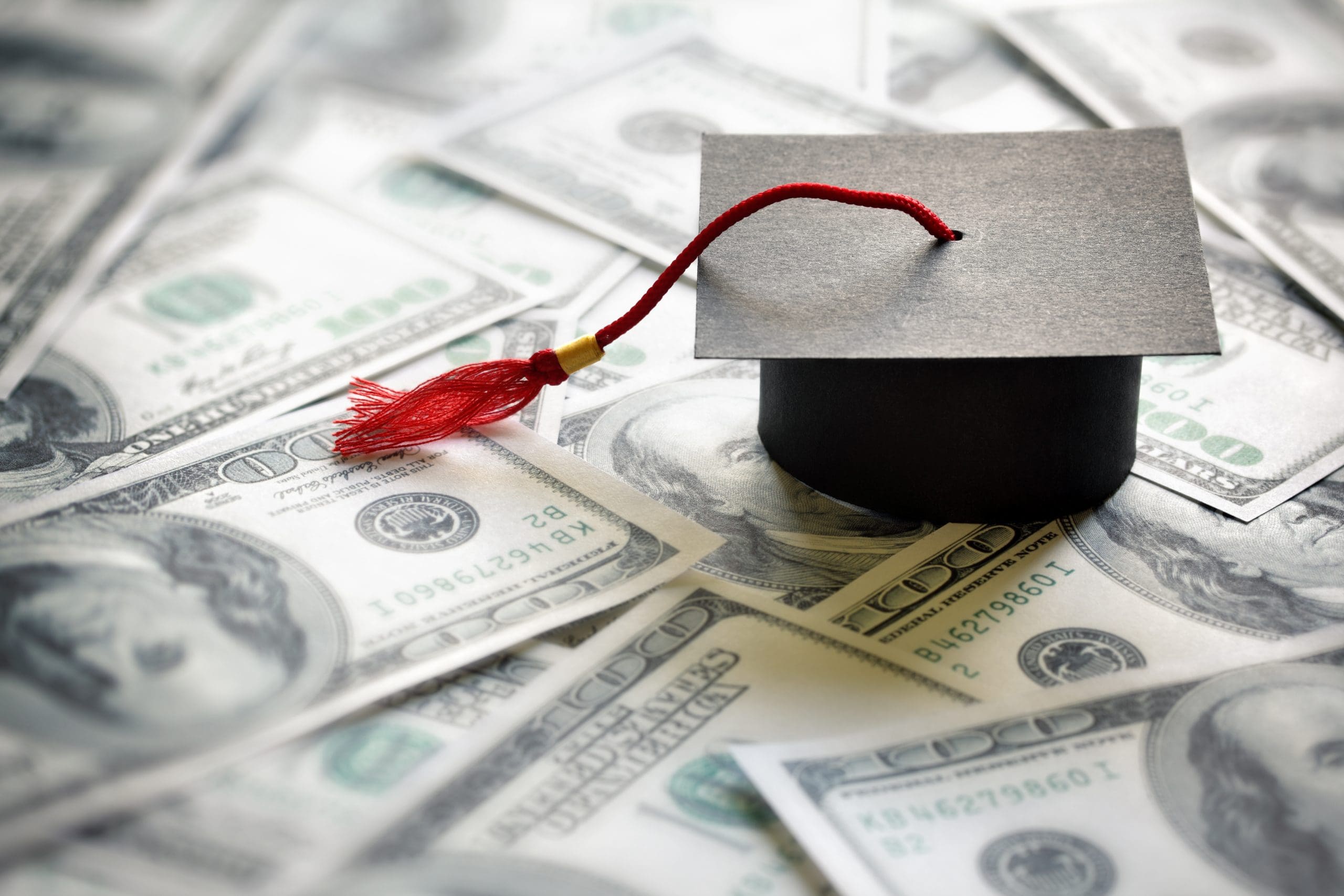 A graduation cap on top of a pile of money.